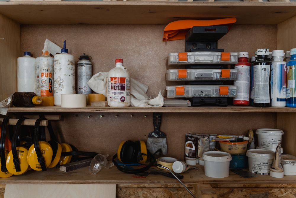 Wooden shelf with hand tools, paint supplies and safety gear in a workshop