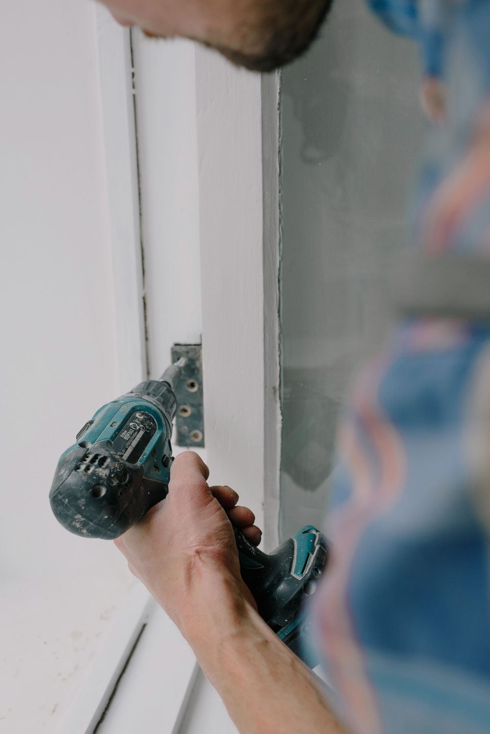 Tightening a hinge with a screwdriver during a home repair