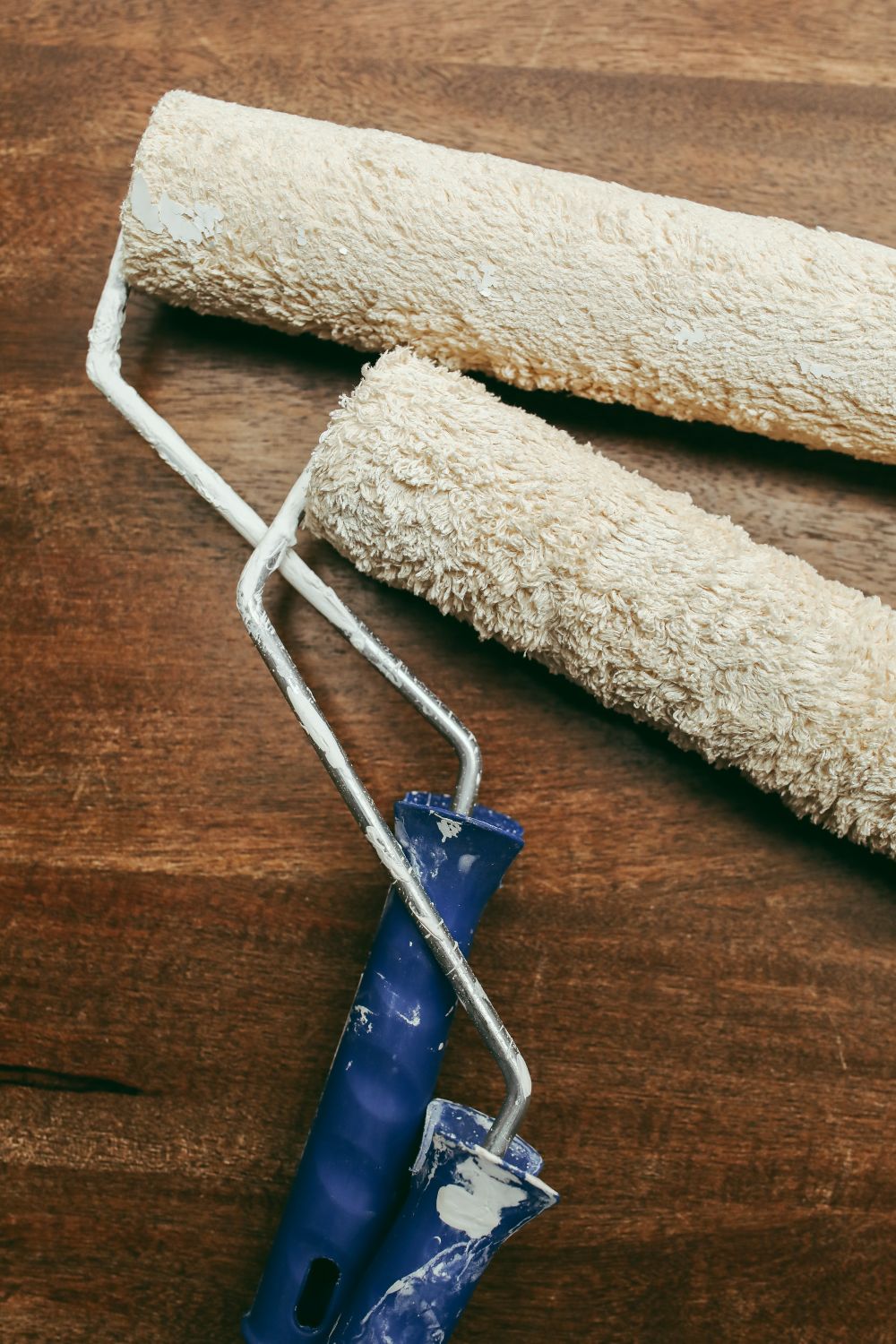 Paint rollers and supplies arranged on a wooden surface