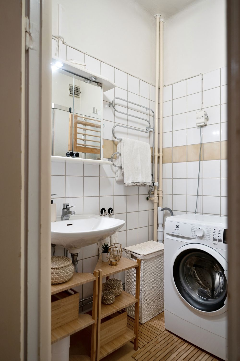 Compact bathroom with wooden shelving above a washbasin